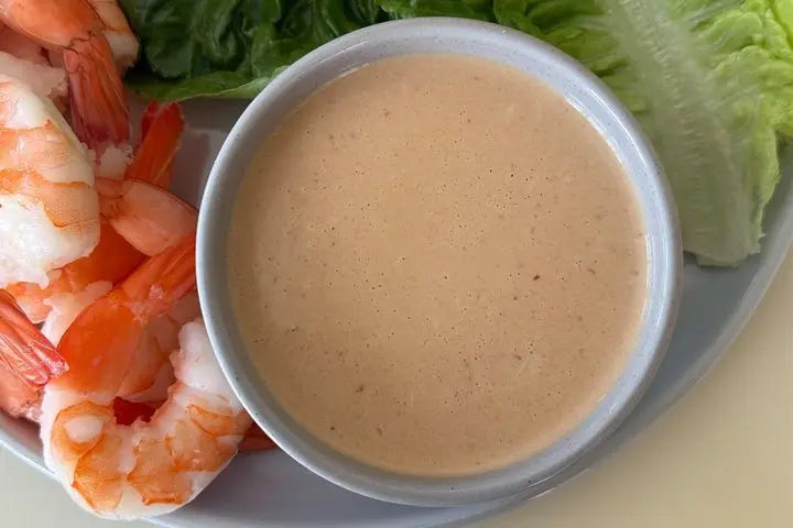 Bowl of creamy sauce with shrimp and lettuce on a plate
