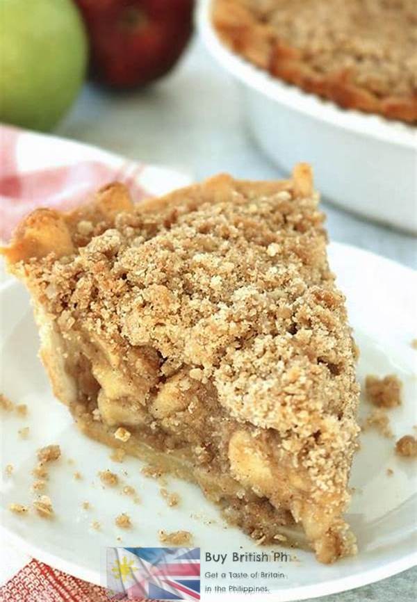 Slice of apple pie with crumb topping on a white plate, surrounded by apples and a dish of pie.