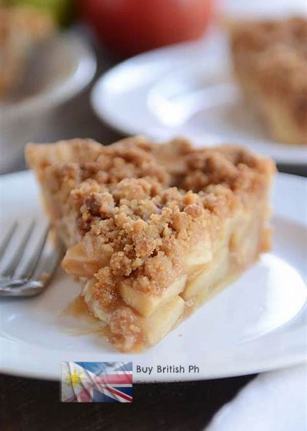 Slice of apple pie with crumble topping on a white plate with a fork, blurred background