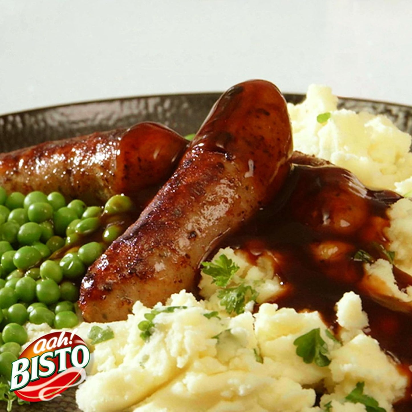 Braised sausages with mashed potatoes and peas on a plate.