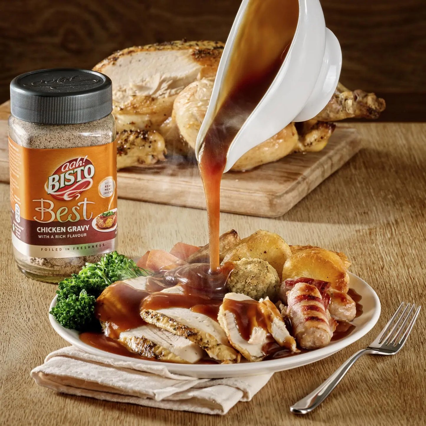 Bisto Best Chicken Gravy being poured over a plate of food on a wooden table.