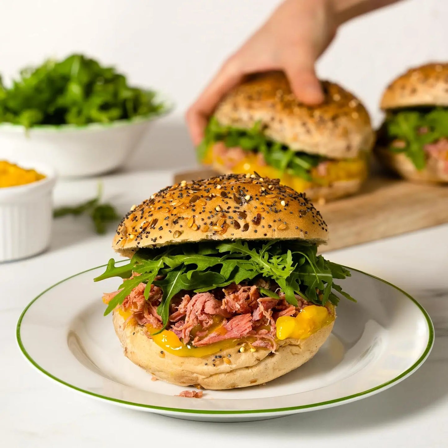Delicious sandwich with arugula and corn on a plate, with more sandwiches in the background.