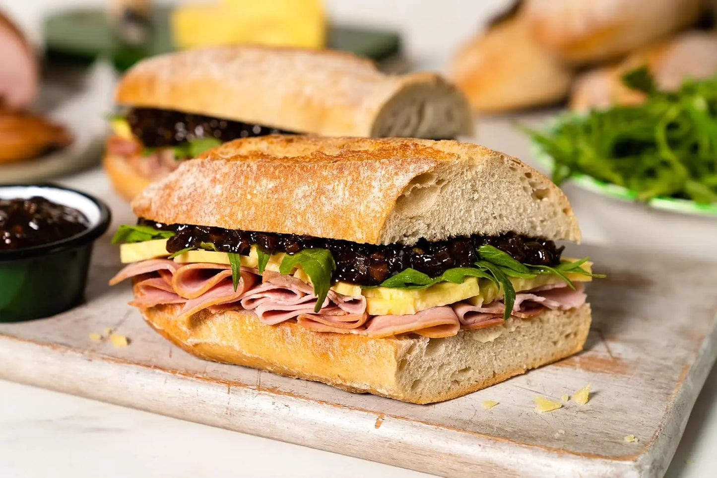 Submarine sandwich with deli meats, cheese, and vegetables on a wooden board.