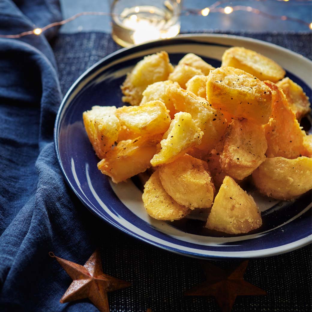 Plate of roasted yams on a blue plate with a blue napkin and star decorations.