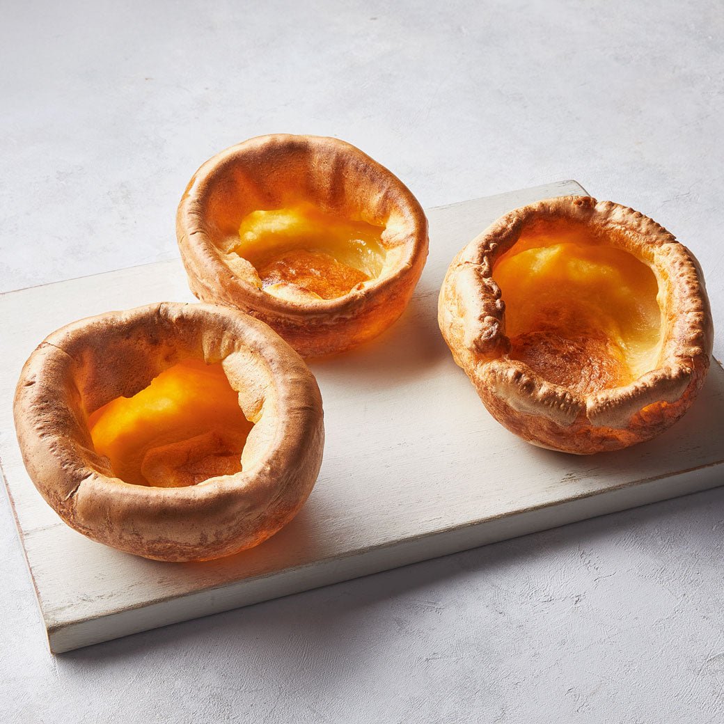 Three bread bowls filled with a yellow custard-like substance on a light gray background.