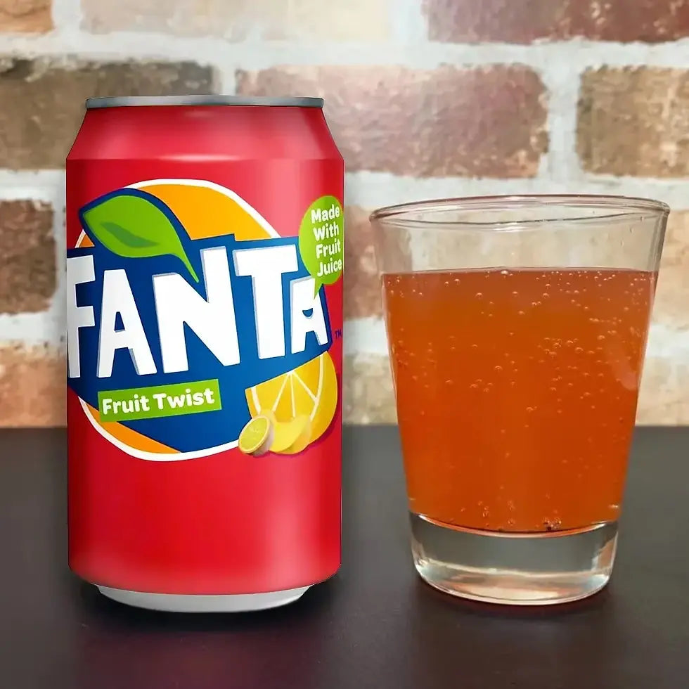 Fanta Fruit Twist can and glass of orange soda on a dark surface with a brick wall background