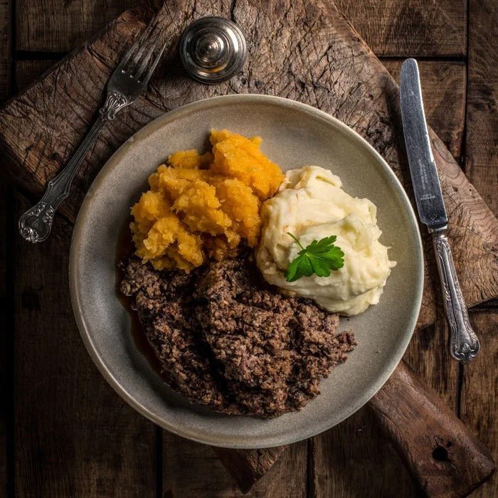 Traditional Scottish dish with haggis, neeps, and tatties on a rustic wooden surface.