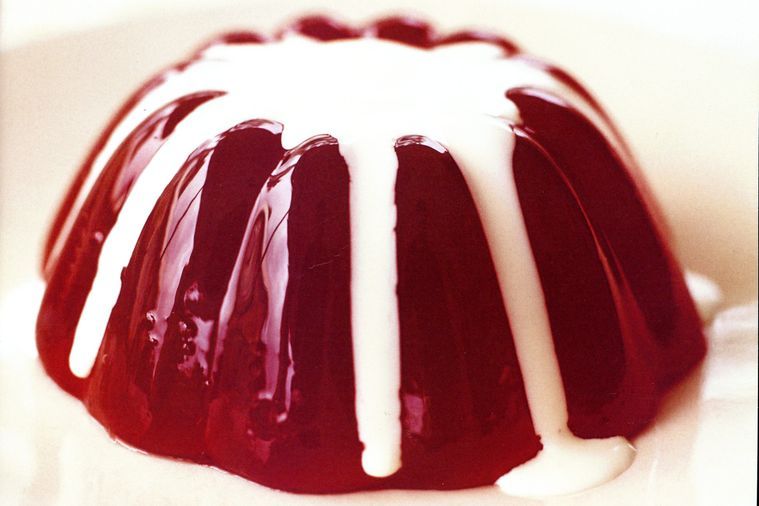 Red jelly mold with white drizzle on a white plate
