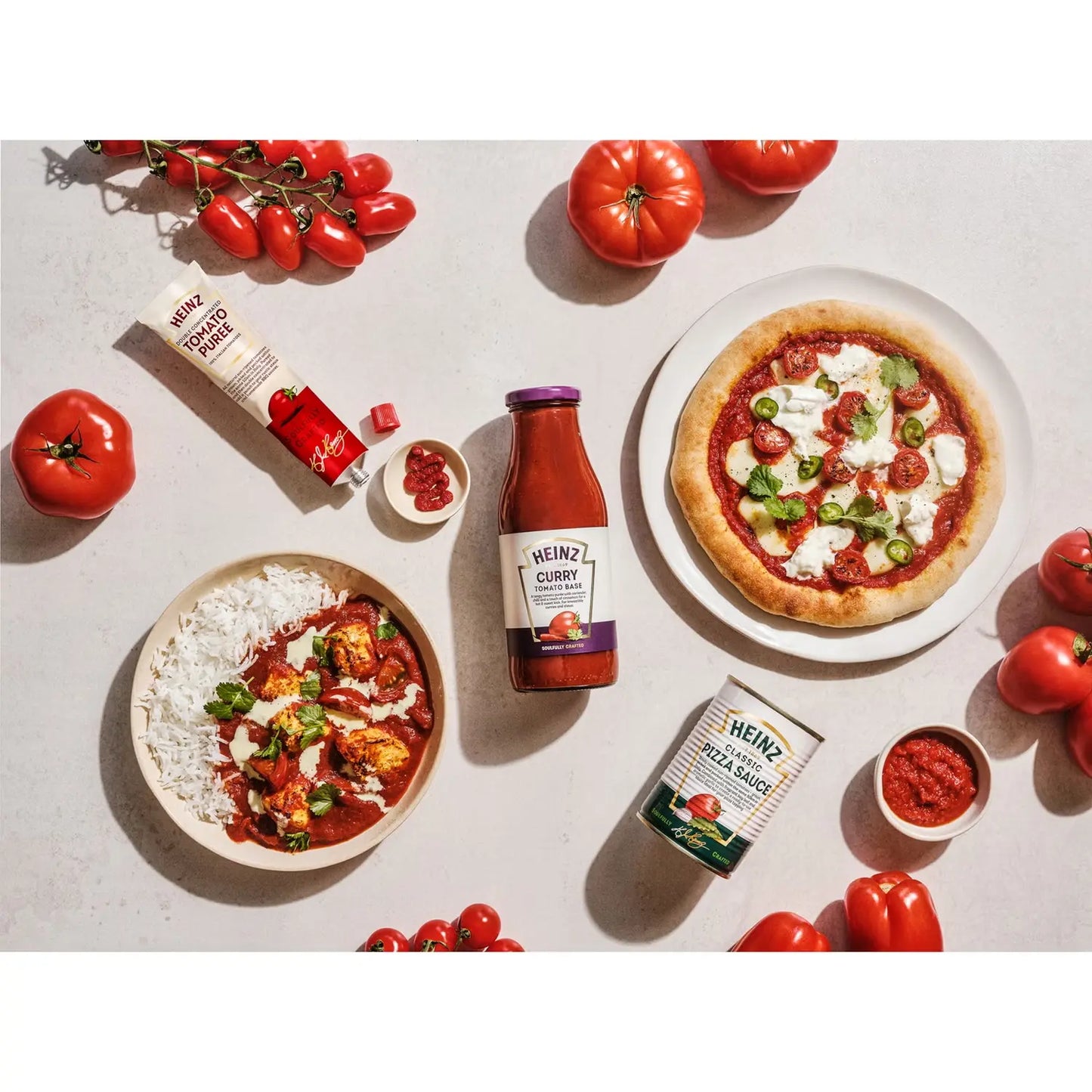 Heinz tomato products with a pizza and side dishes on a light surface.