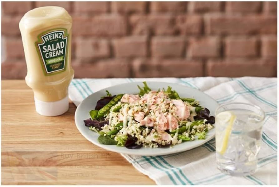 Heinz Salad Cream bottle next to a salad on a wooden table with a brick wall background