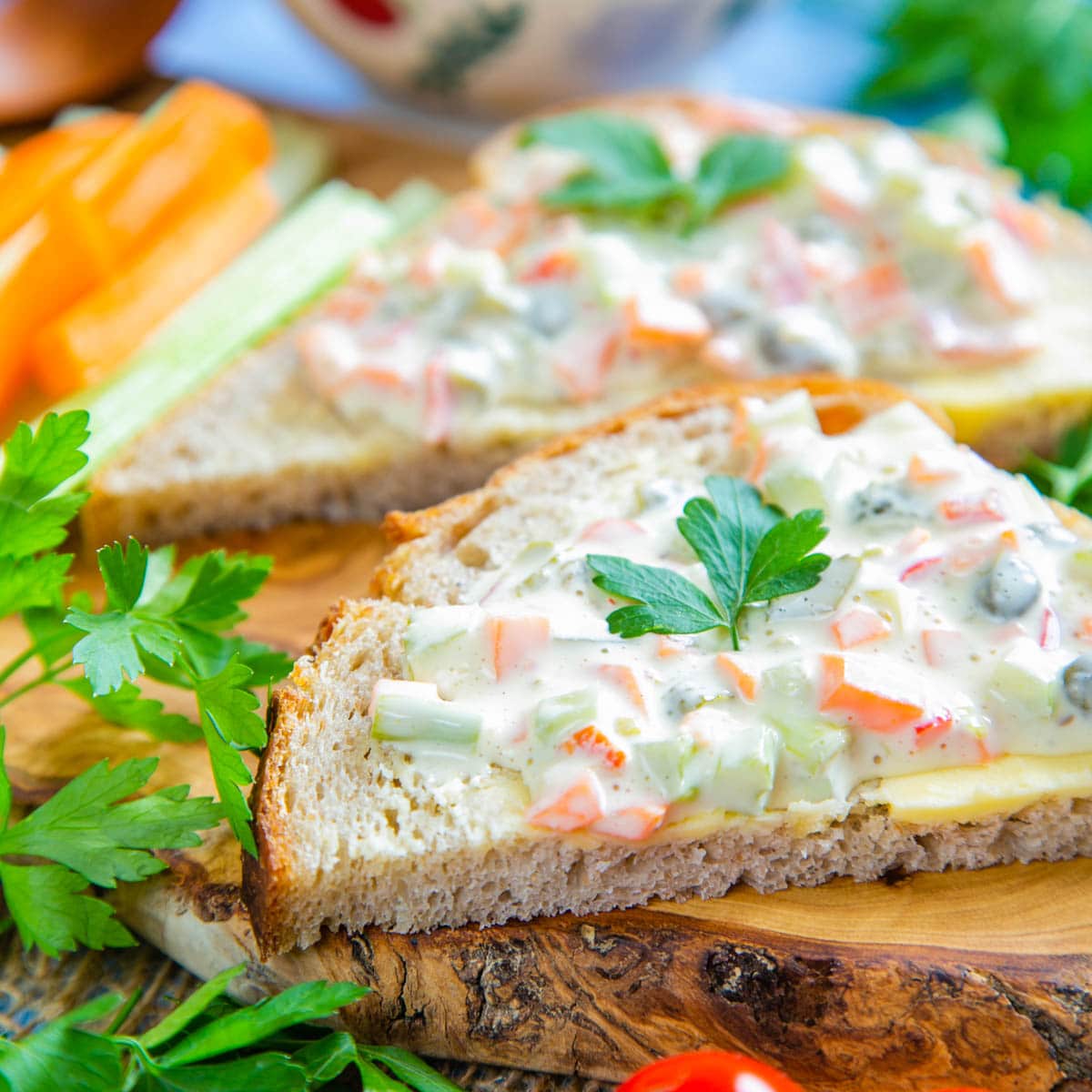 Slice of bread with salad on a wooden board, garnished with herbs.