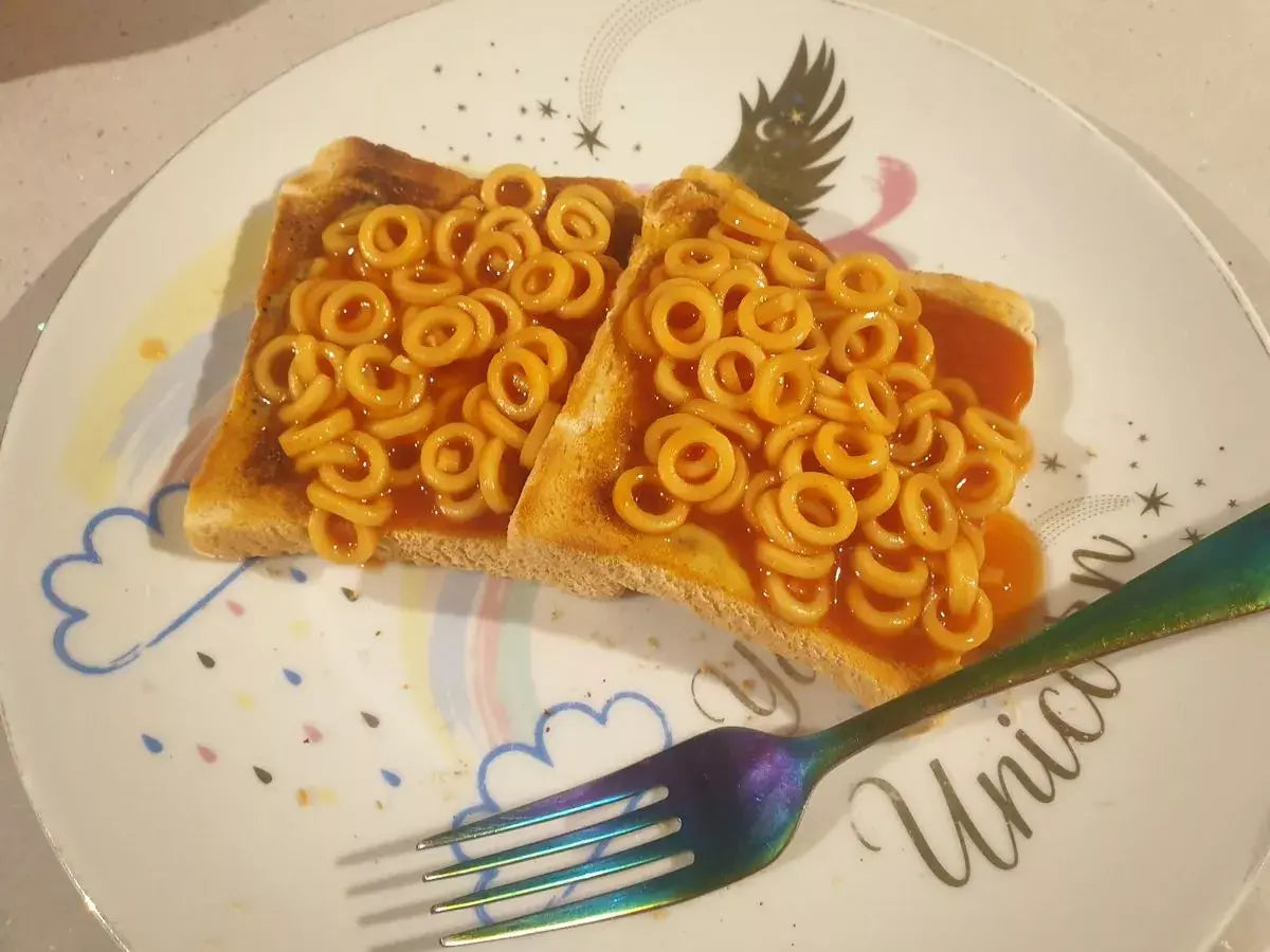 Two slices of toast with spaghetti hoops and in tomato sauce on a plate with a unicorn design.