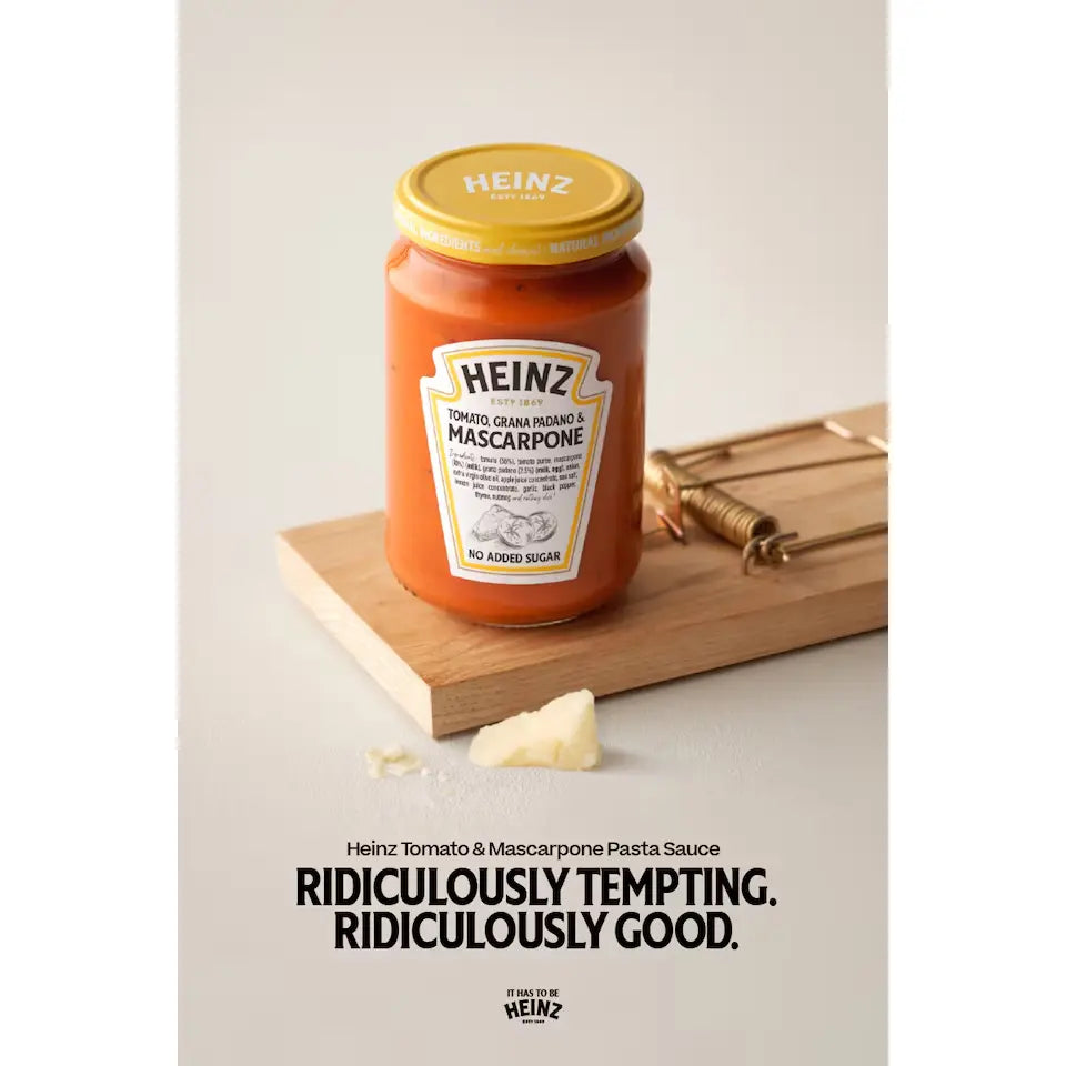 Heinz Tomato & Mascarpone Pasta Sauce jar on a wooden board with cheese, against a light background.