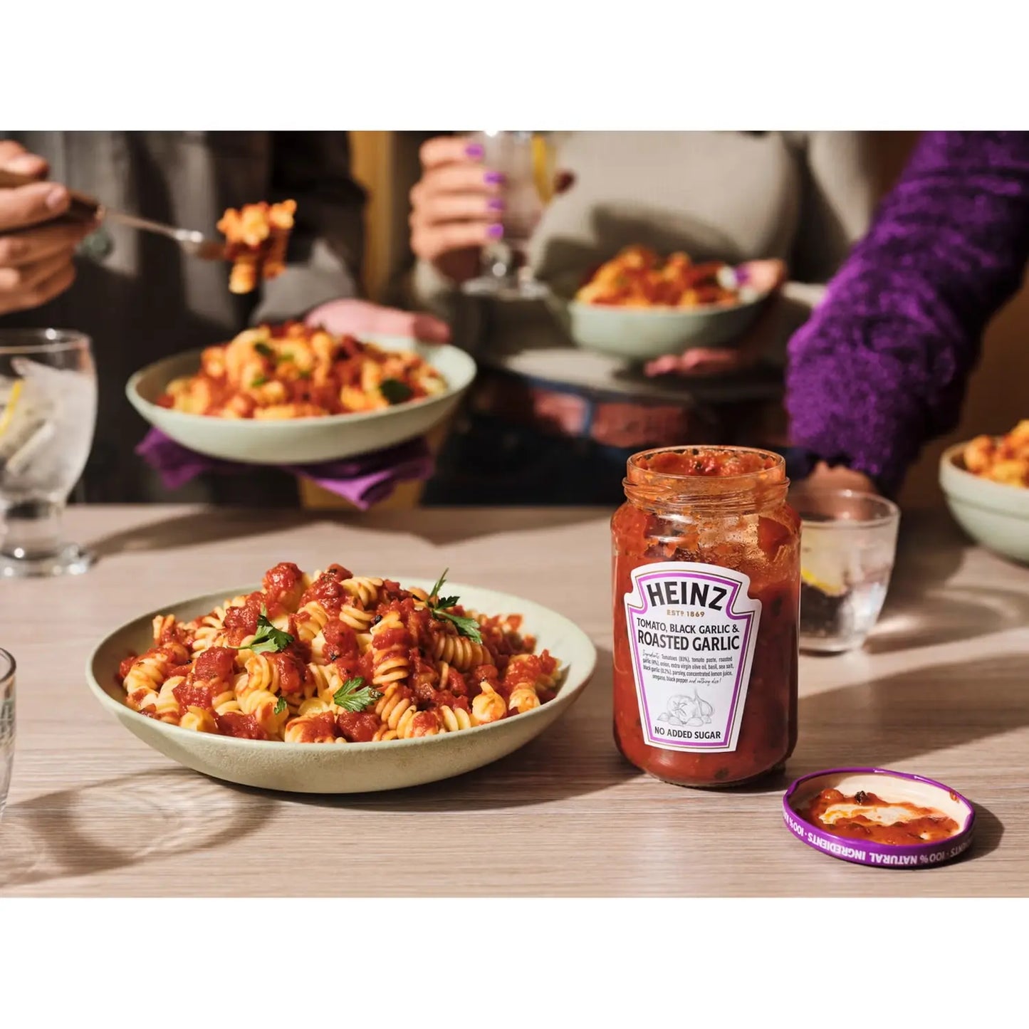 Pasta dish with Heinz roasted garlic sauce on a table with people eating in the background