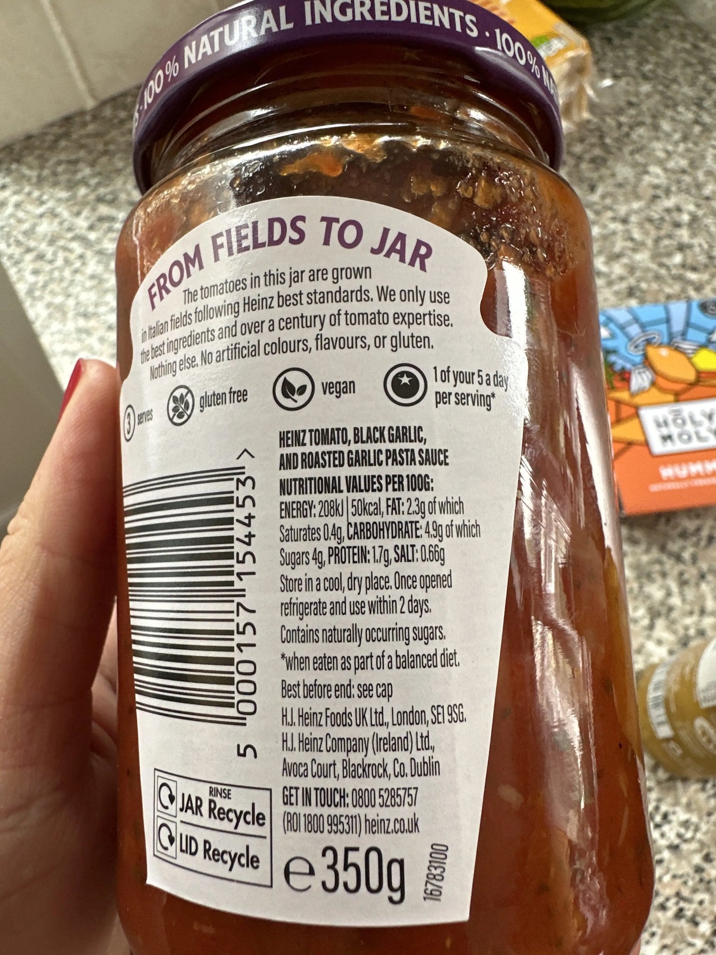 Hand holding a jar of Heinz pasta sauce with a visible label.