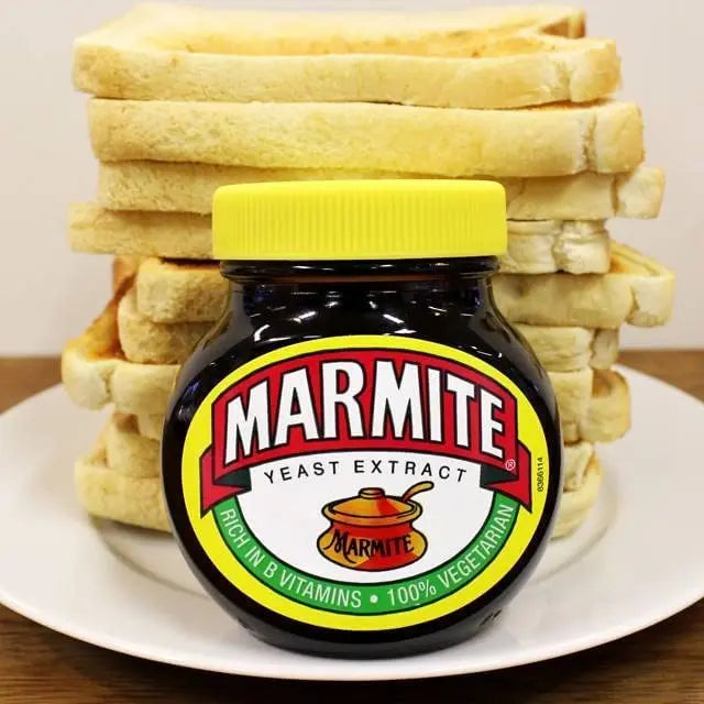 Jar of Marmite yeast extract with a stack of toast on a white plate