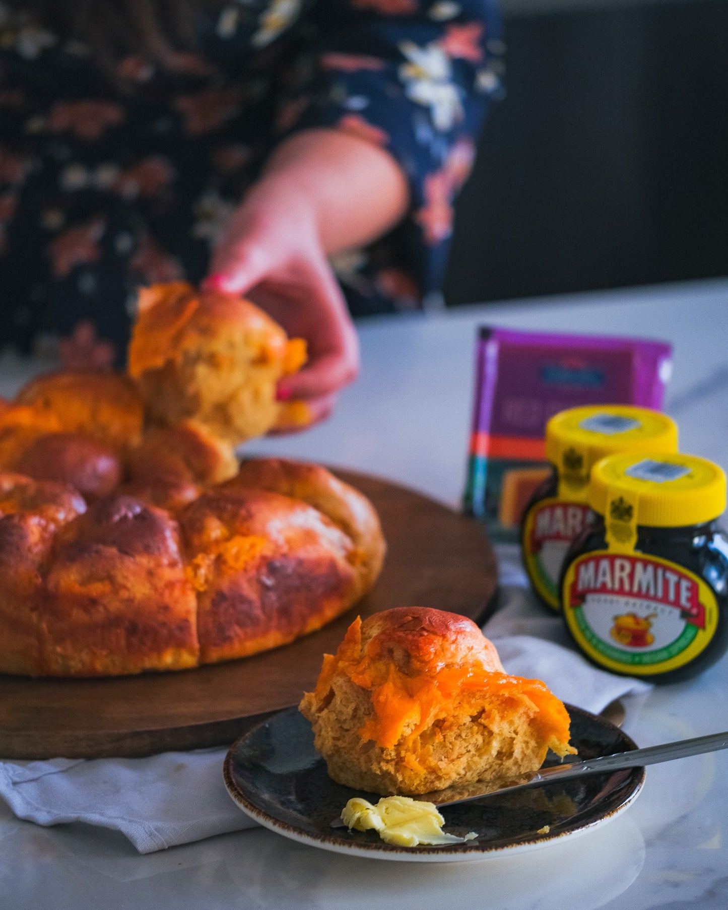 Bread rolls on a wooden board with Marmite jars in the background