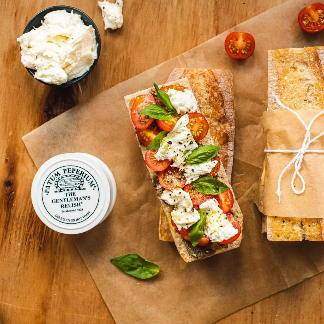 Bruschetta with tomatoes and cheese on a wooden surface with a container of relish.