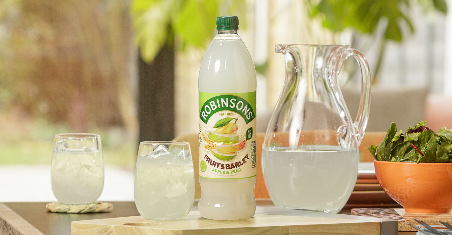 Robinsons fruit & barley drink with glasses and a pitcher on a table outdoors.