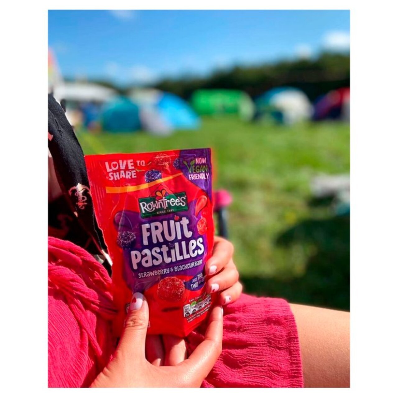 Person holding a packet of Rowntrees Fruit Pastilles with a blurred outdoor background