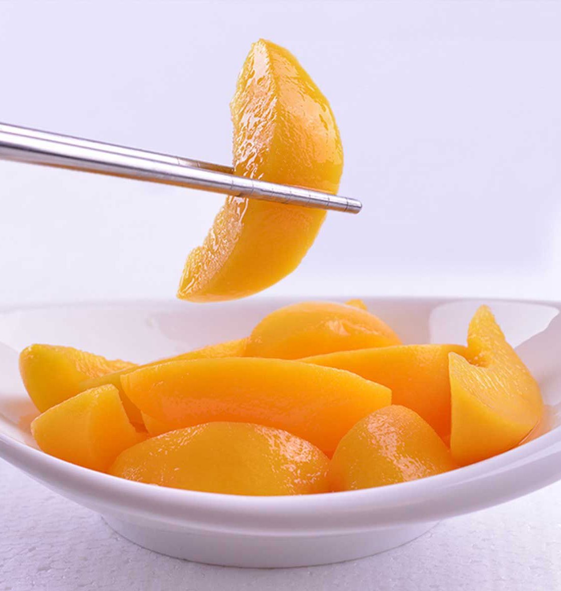 Yield of yellow fruit pieces in a white bowl with chopsticks lifting one piece.