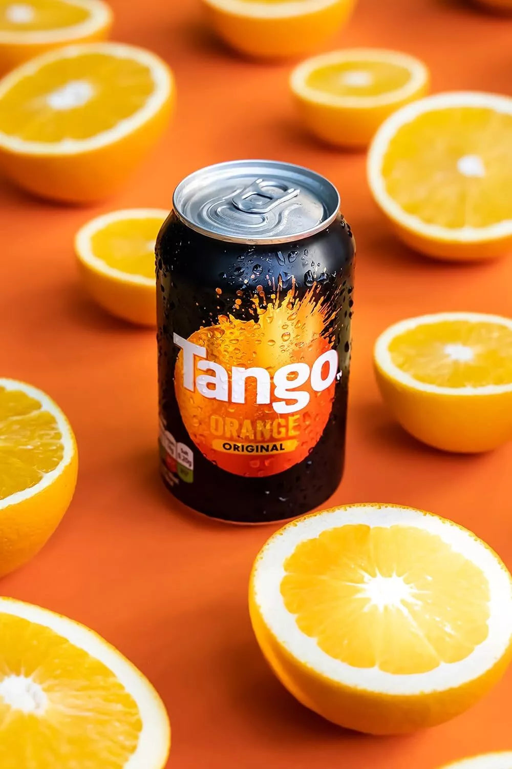 Tango orange soda can surrounded by sliced oranges on an orange background