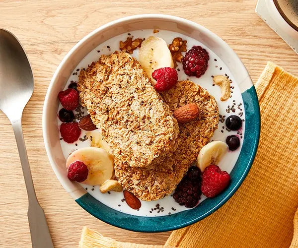 Breakfast bowl with granola, fruits, and nuts on a wooden table