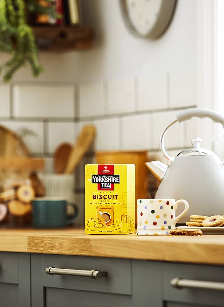 Yorkshire Tea box on a kitchen counter with a teapot and cookies.