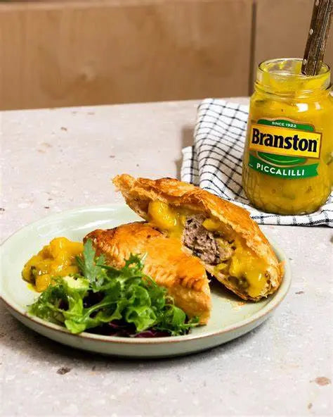 Pasty with cheese and salad on a plate with a jar of Branston Pickle.