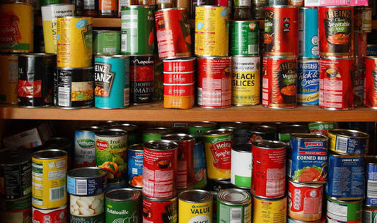 British cupboard shelf filled with tinned food including baked beans, soup and vegetables