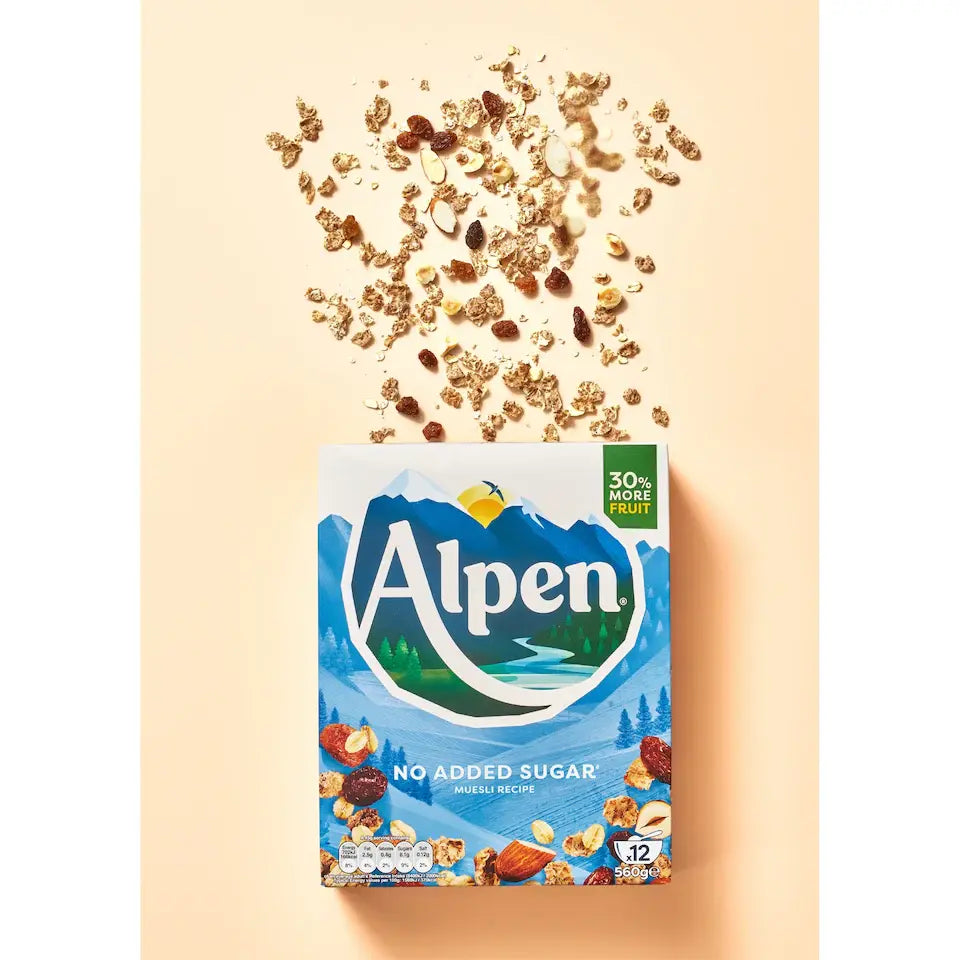 Alpen cereal box with scattered cereal pieces on a beige background