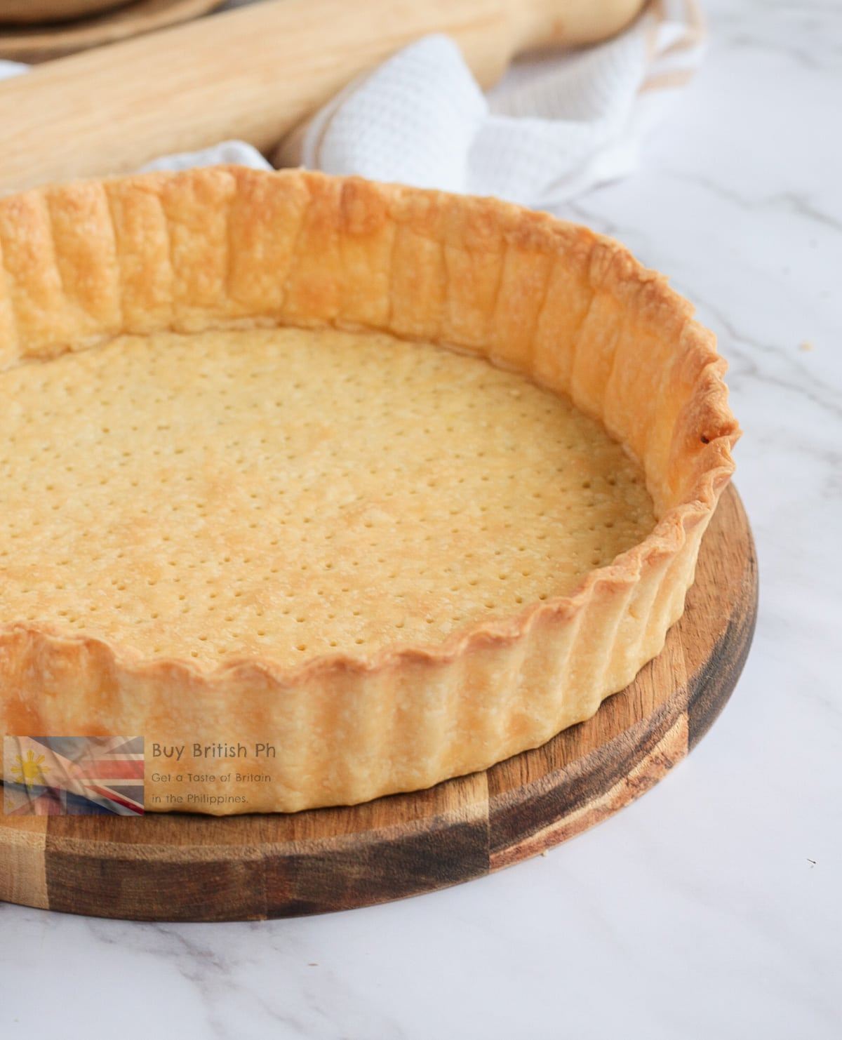 Pastry tart shell on a wooden board with a white background