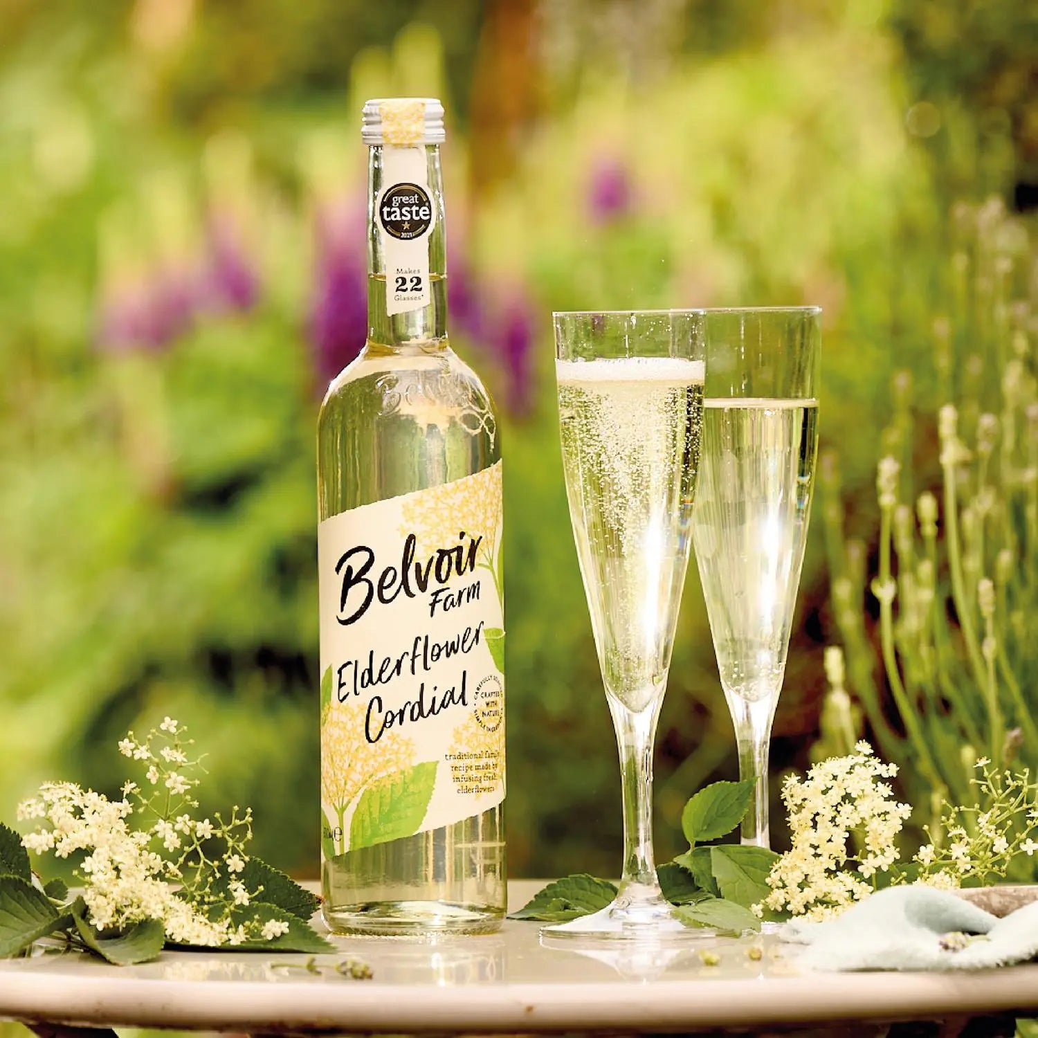 Belvoir Elderflower Cordial bottle with two glasses outdoors