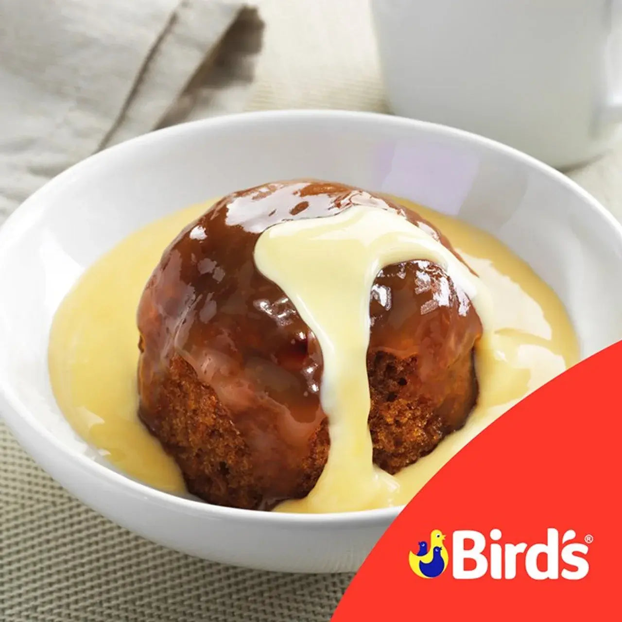 Dessert with a glaze in a white bowl on a textured surface, featuring the Birds logo.