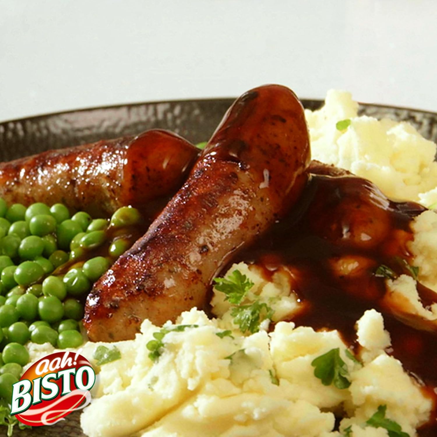 Braised sausages with mashed potatoes and peas on a plate.