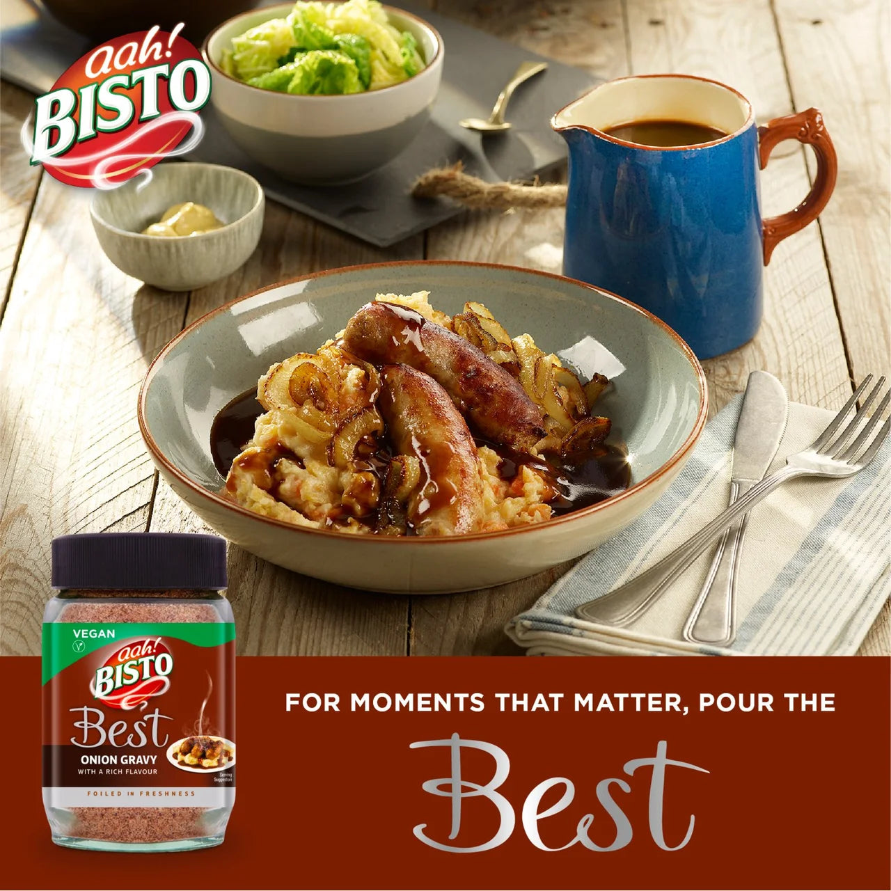 Bisto Best onion gravy jar with a bowl of food and a cup on a wooden table.