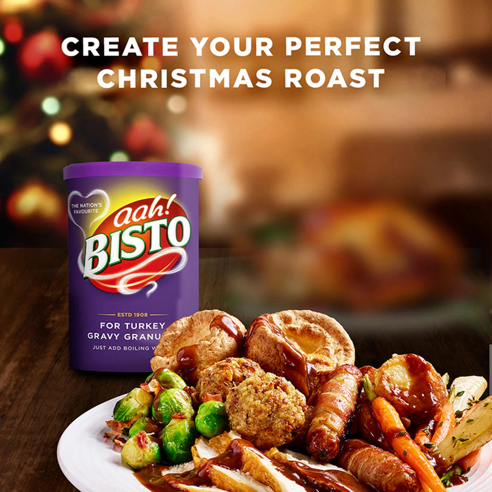 Bisto gravy granules with a Christmas roast dinner on a table.