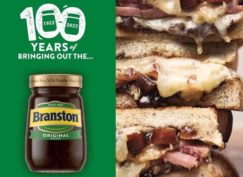 Branston pickle jar with a sandwich featuring Branston pickle on a green background celebrating 100 years.