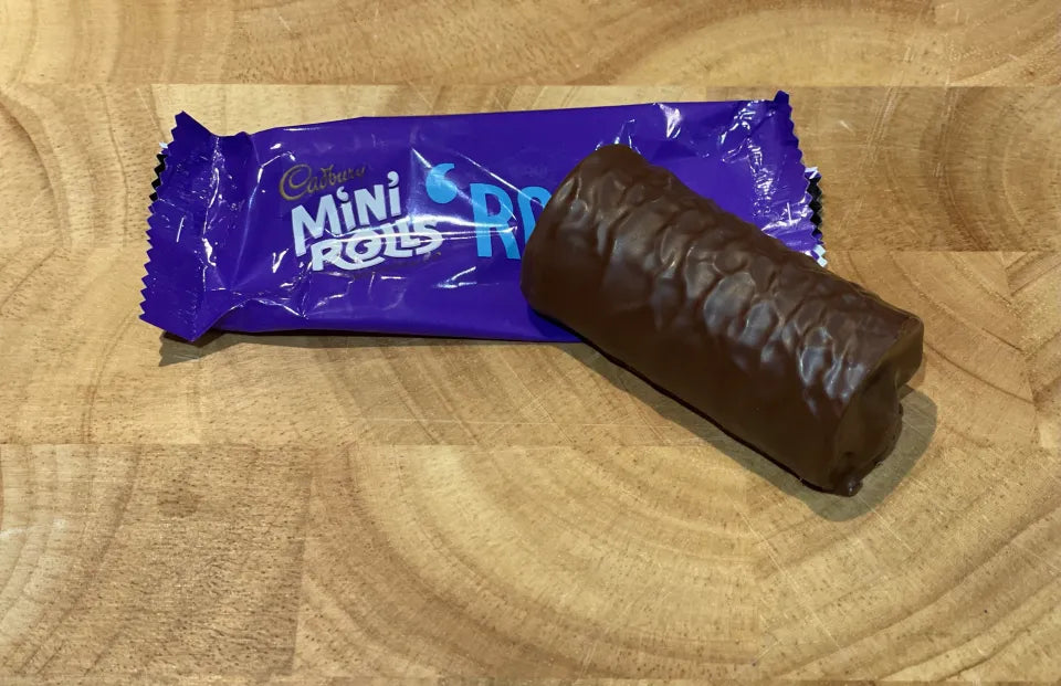 Cadbury Mini Rolls chocolate roll on a wooden surface