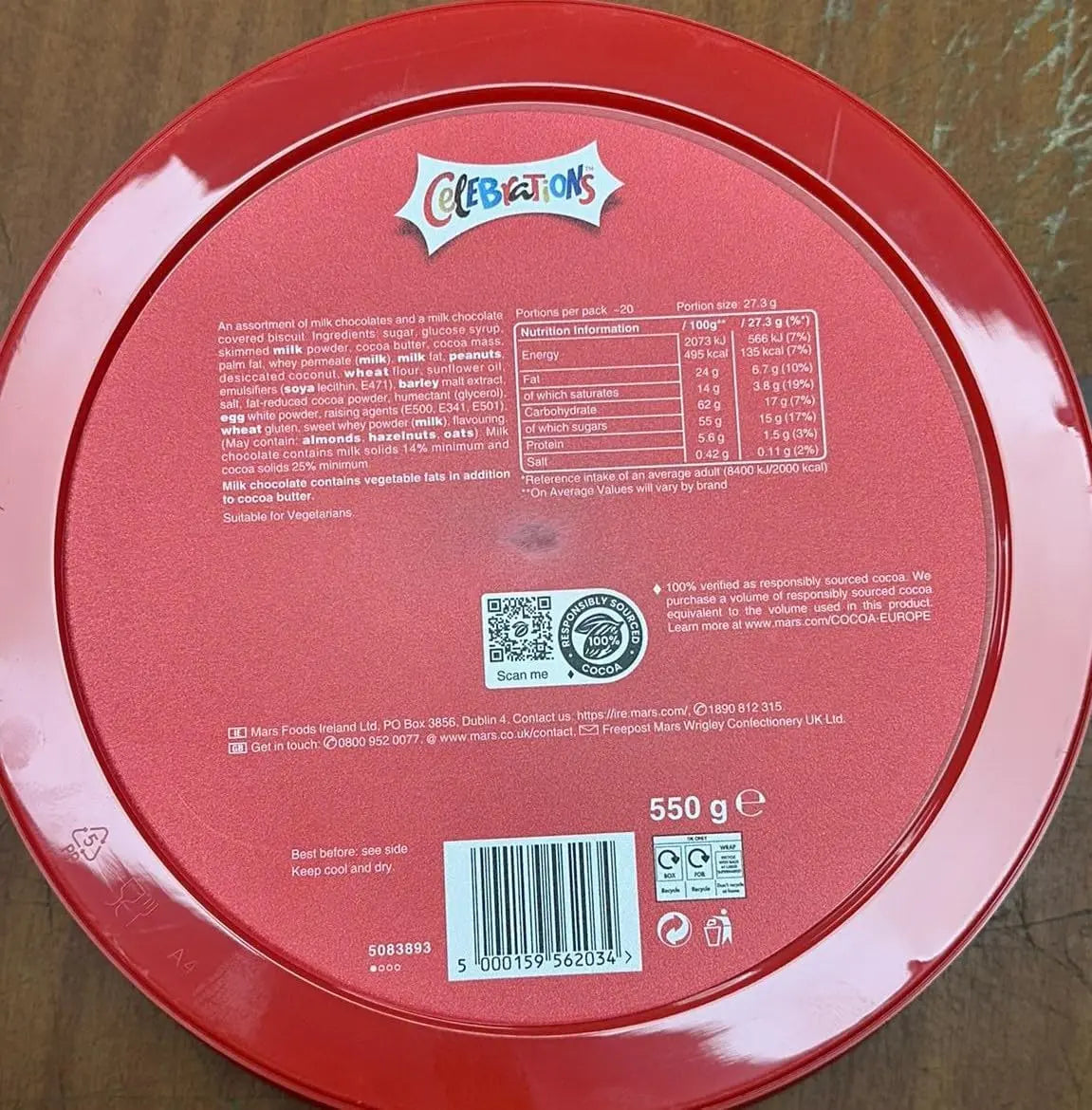 Red container lid with 'Celebrations' branding and nutritional information on a wooden surface.