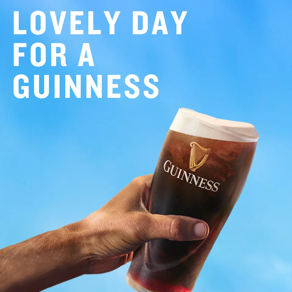 Hand holding a pint of Guinness beer with 'Lovely Day for a Guinness' text on a blue background