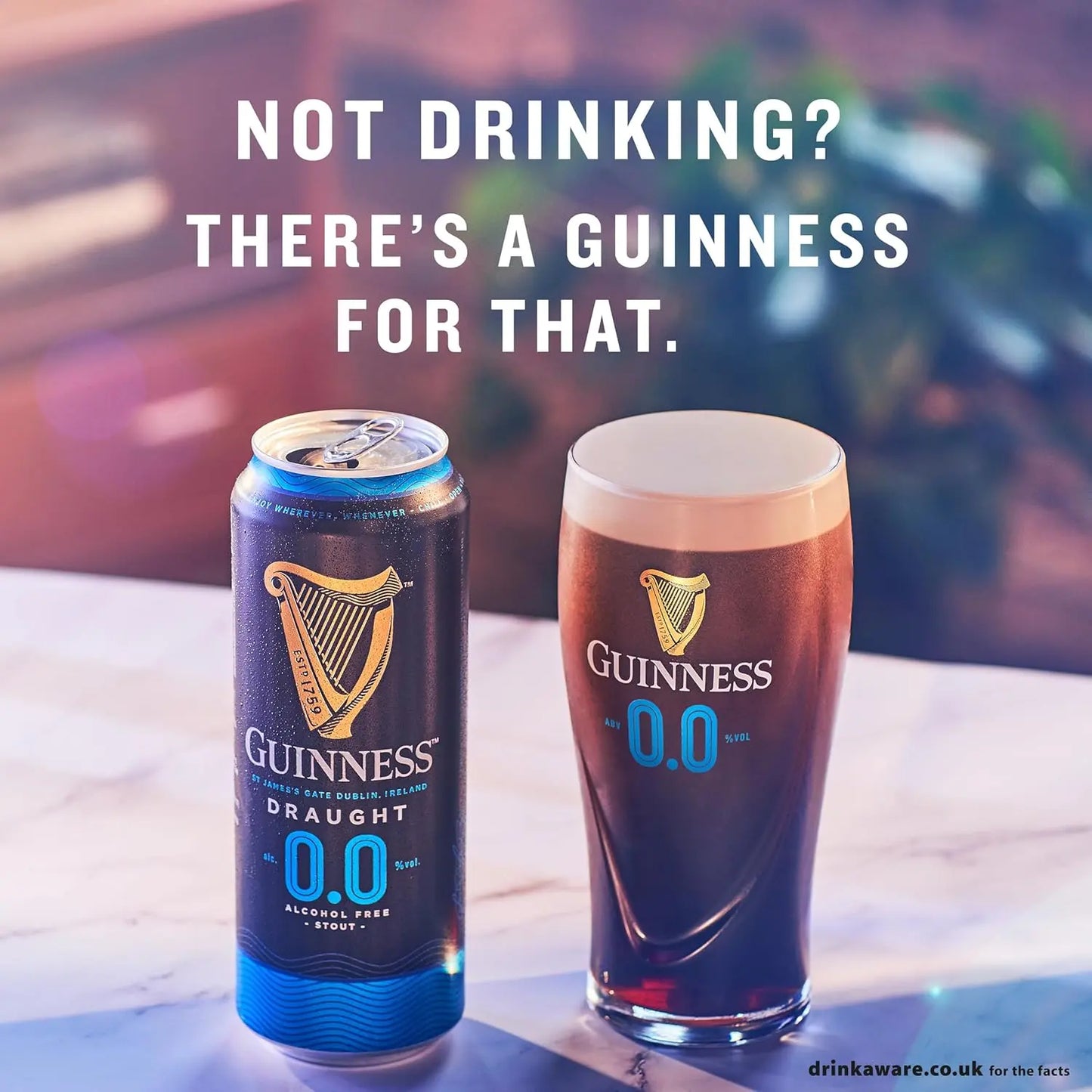 Guinness Draught 0.0 can and glass on a table with promotional text.