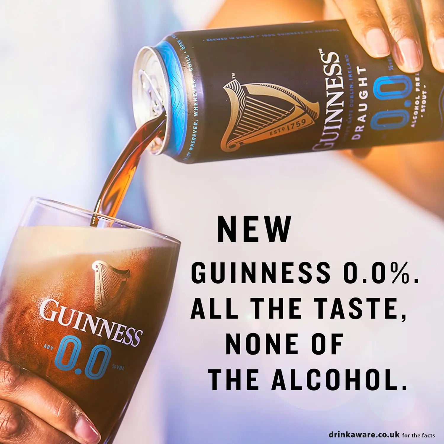 Guinness 0.0% can being poured into a glass with promotional text.