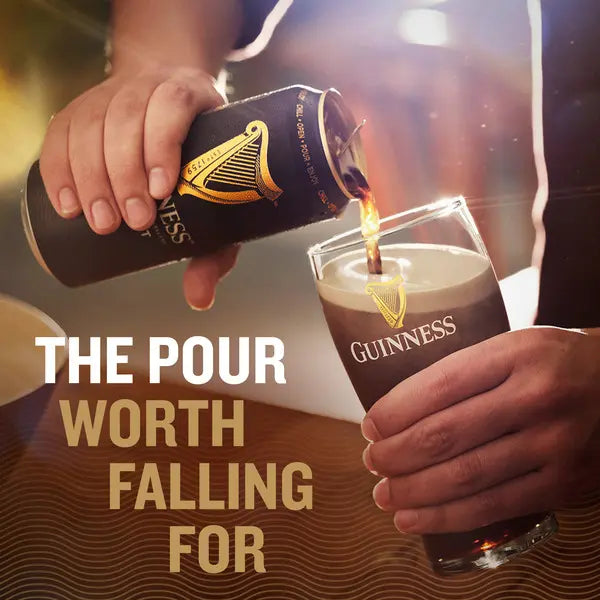 Person pouring Guinness beer into a glass with the brand logo visible.