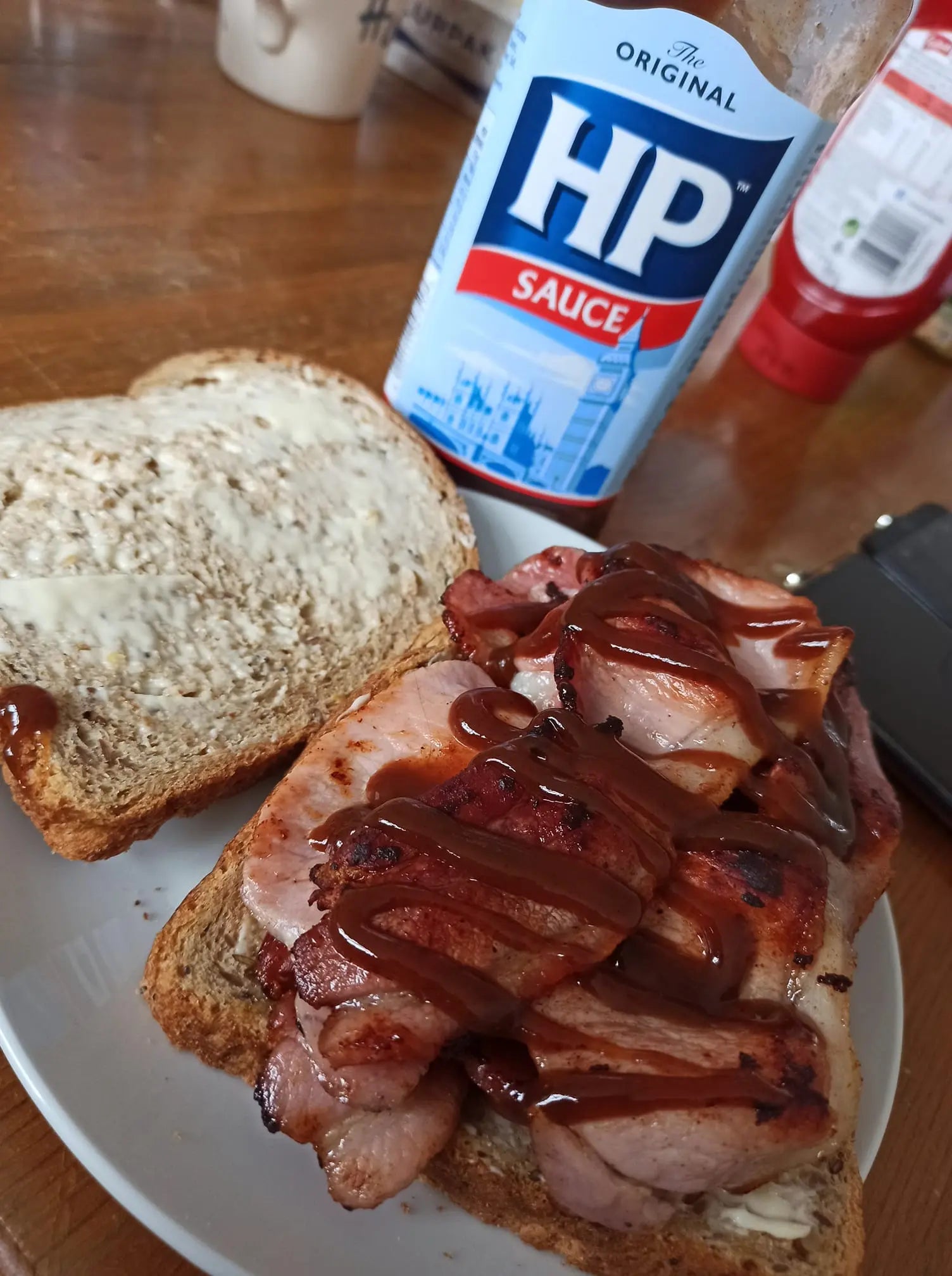 Bacon and HP sauce on toast with a bottle of HP sauce in the background.