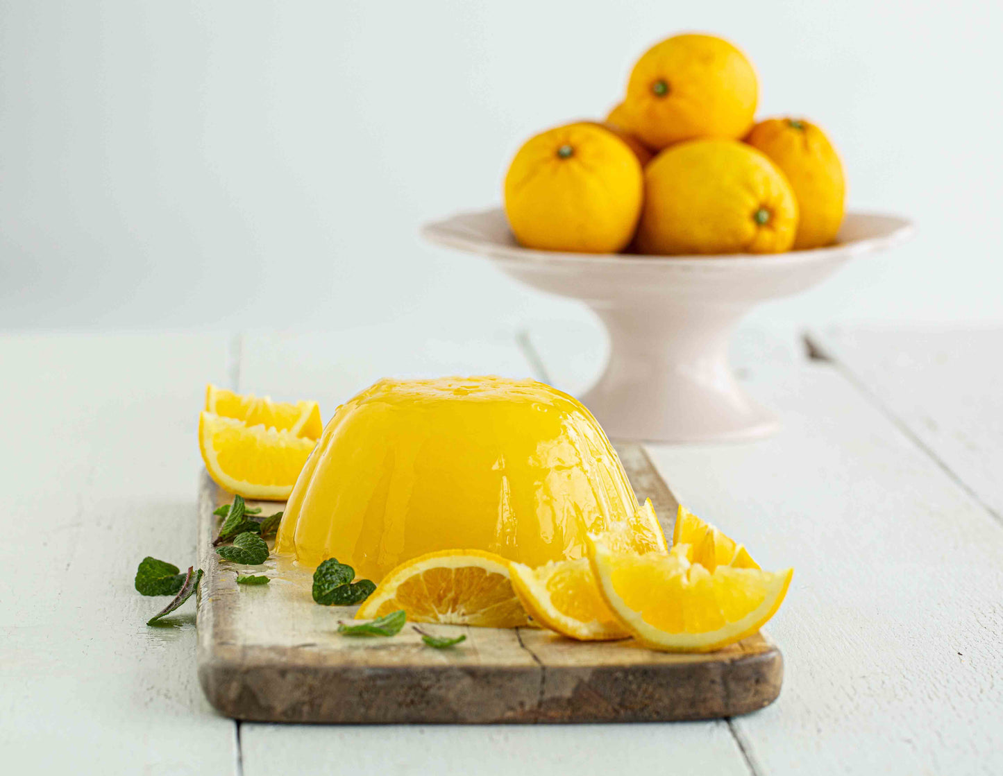 Yellow jelly dessert with lemon slices on a wooden board, lemons in the background.