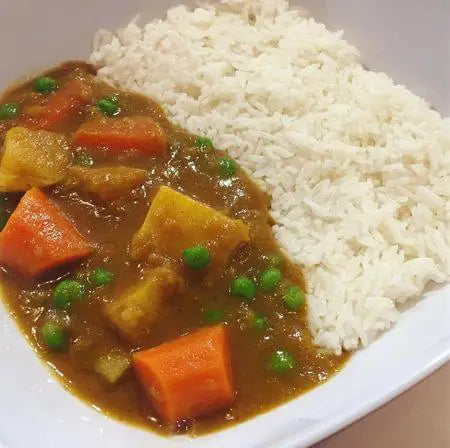 Curry dish with vegetables and rice on a white plate
