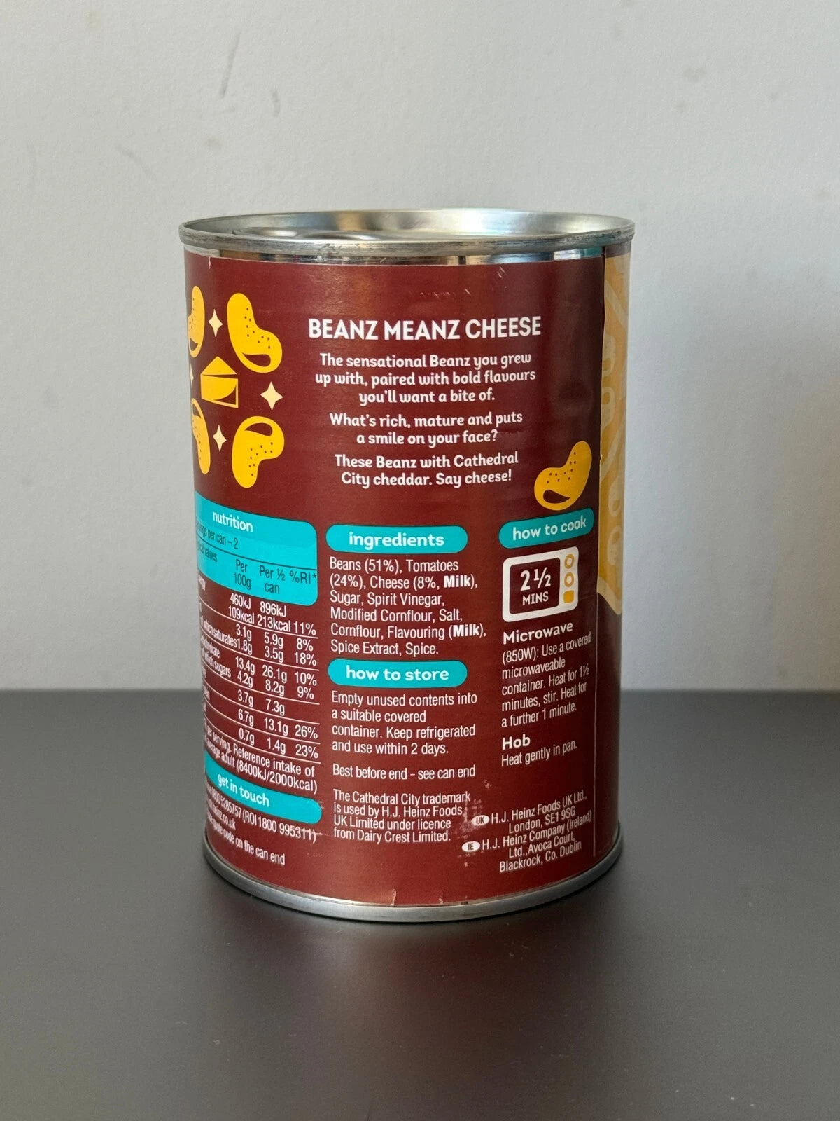 Can of 'Beanz Meanz Cheese' with nutritional information on a gray background