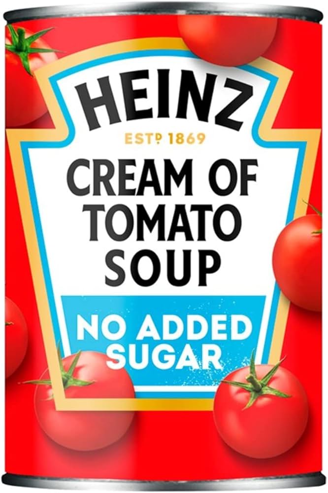 Can of Heinz Cream of Tomato Soup with no added sugar on a red background with tomatoes.