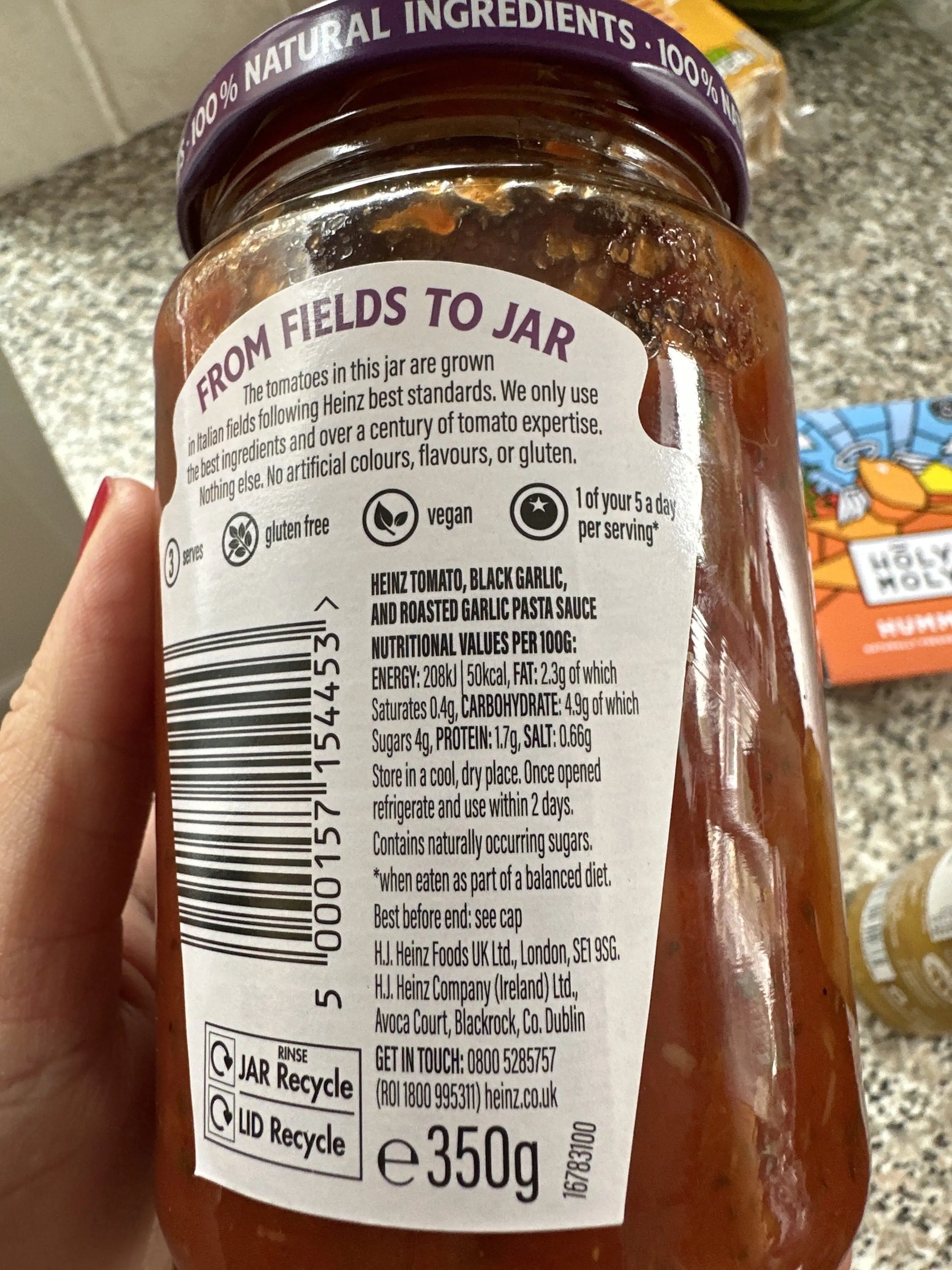 Hand holding a jar of Heinz pasta sauce with a visible label.